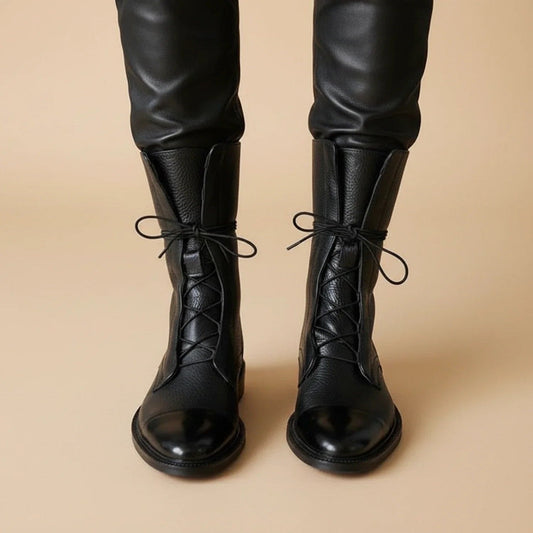 Front view of black lace-up ankle boots with rounded-looking glossy toe caps and tall padded tongues.