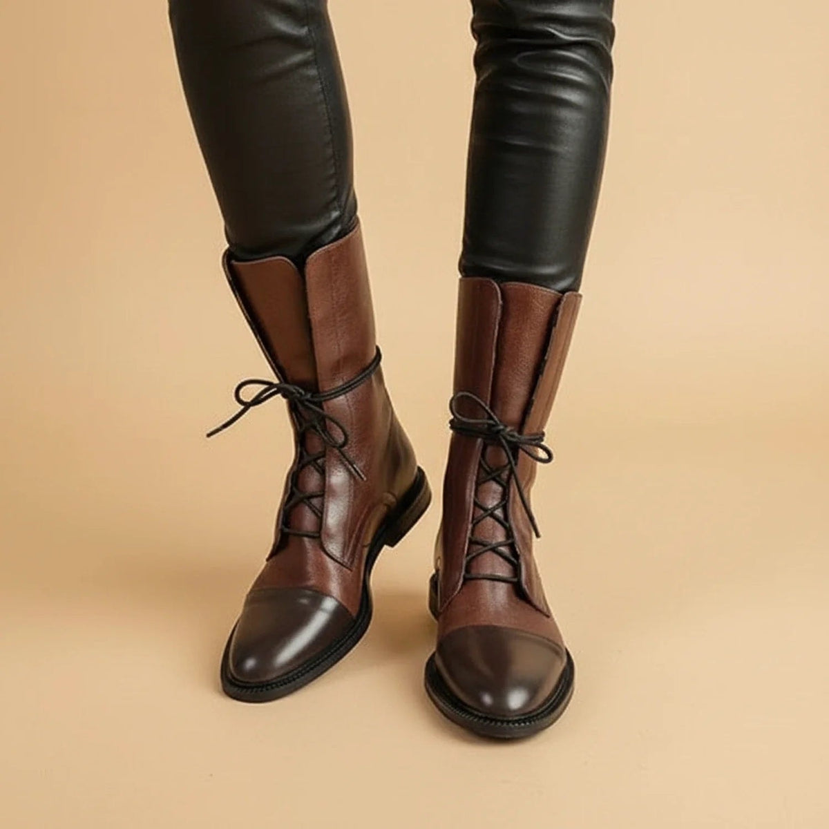 Brown ankle boots styled with black leggings, showing front lacing, contrasting dark toe caps, and low block heels.