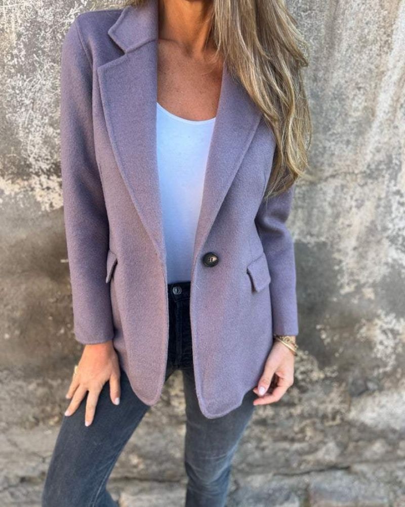 Muted lavender blazer jacket featuring notched lapels, a single-button front, and flap pockets over a white top.