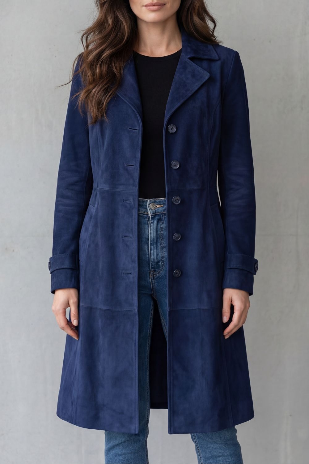 Navy blue longline coat worn open at the neckline, showing its notched collar, button front, cuff details, and extended hem.