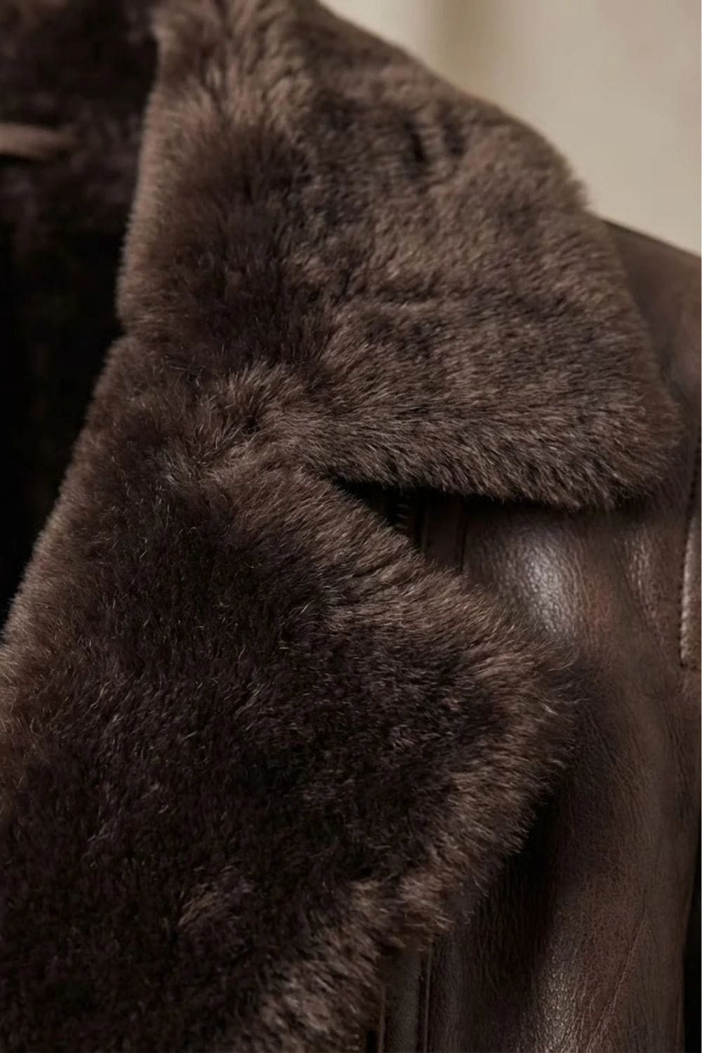 Woman viewed from behind wearing a hip-length zip-front jacket with a faux fur collar, welt pockets and ribbed sleeve detail._10