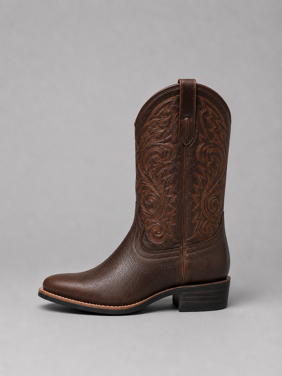 Side view of a brown embroidered cowboy boot highlighting the pull-on shaft, pointed toe, stacked block heel, and detailed stitching.