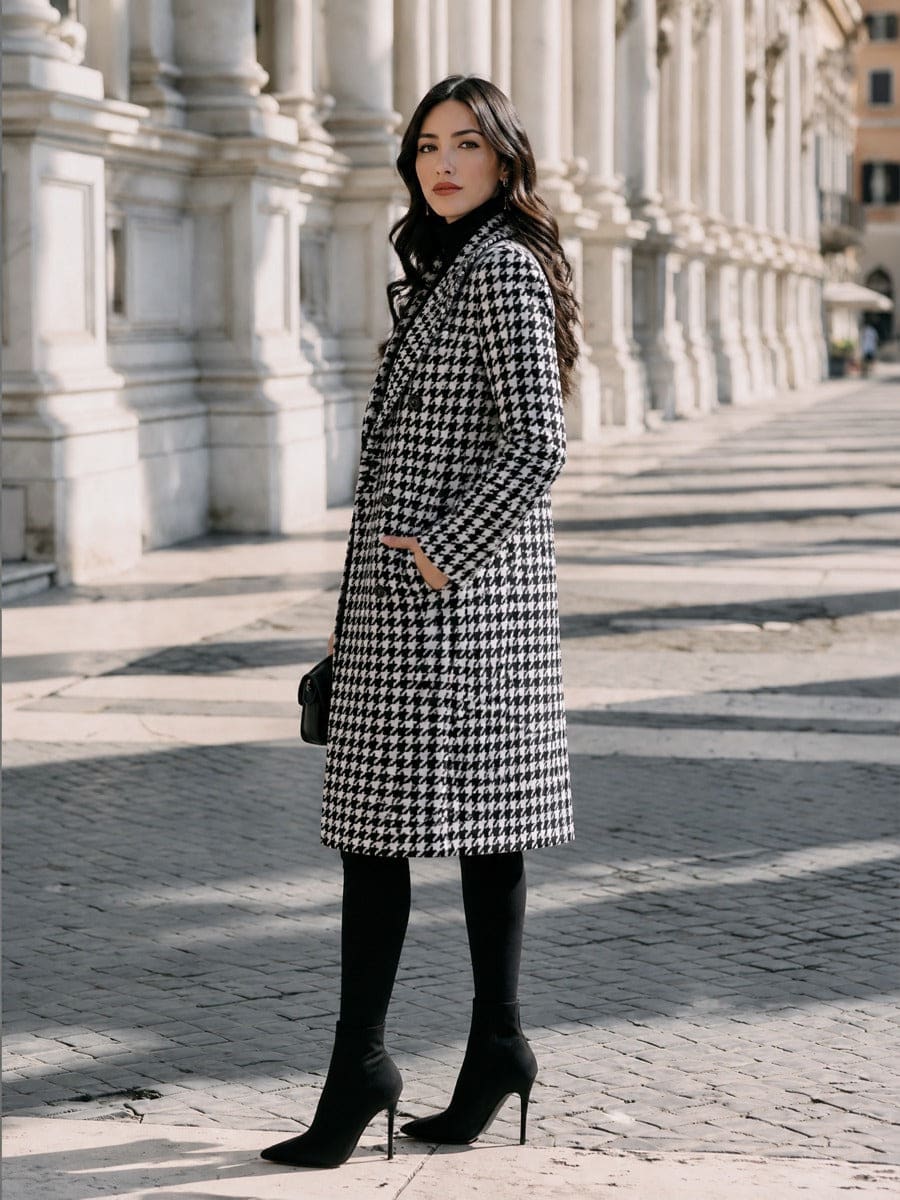 Woman wearing a long double-breasted houndstooth coat with notch lapels, worn open over a polo neck with knee-high boots._2
