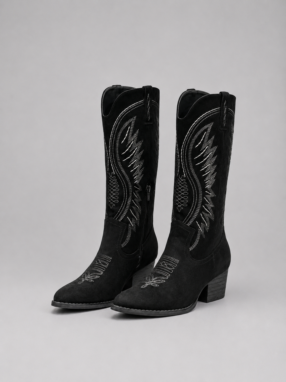 Pair of black cowboy boots with contrasting Western stitching, pointed toes, side pulls, and block heels.