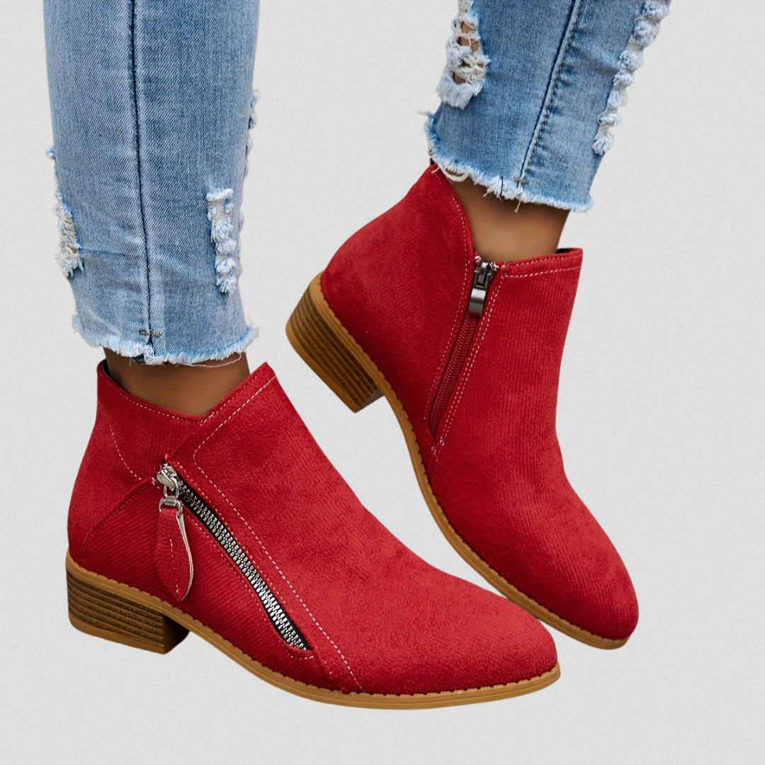 Red ankle boots with side zippers and low stacked block heels shown worn with frayed cropped jeans.