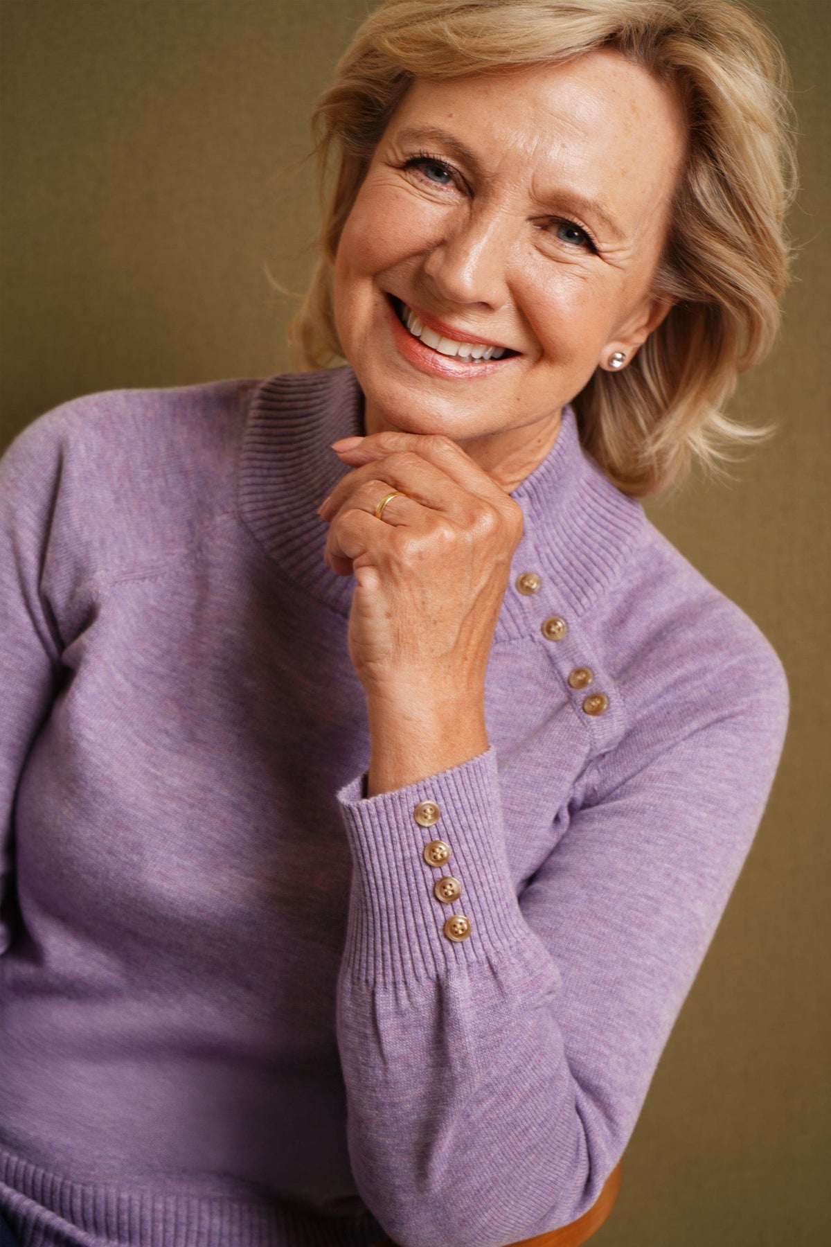 Woman wearing a long sleeve knitted jumper with a funnel collar, buttons along one side of the neck and buttoned ribbed cuffs._5