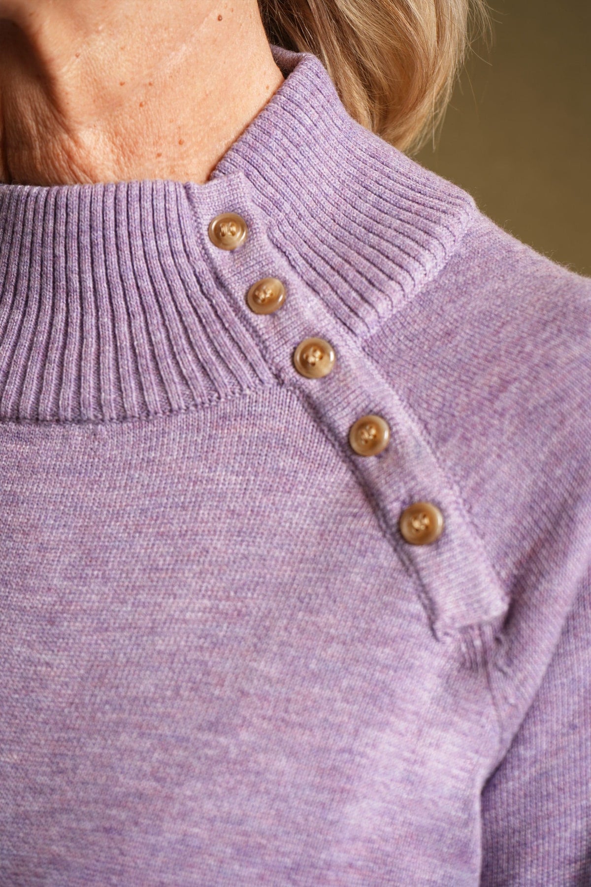 Woman wearing a long sleeve knitted jumper with a funnel collar, buttons along one side of the neck and buttoned ribbed cuffs._6