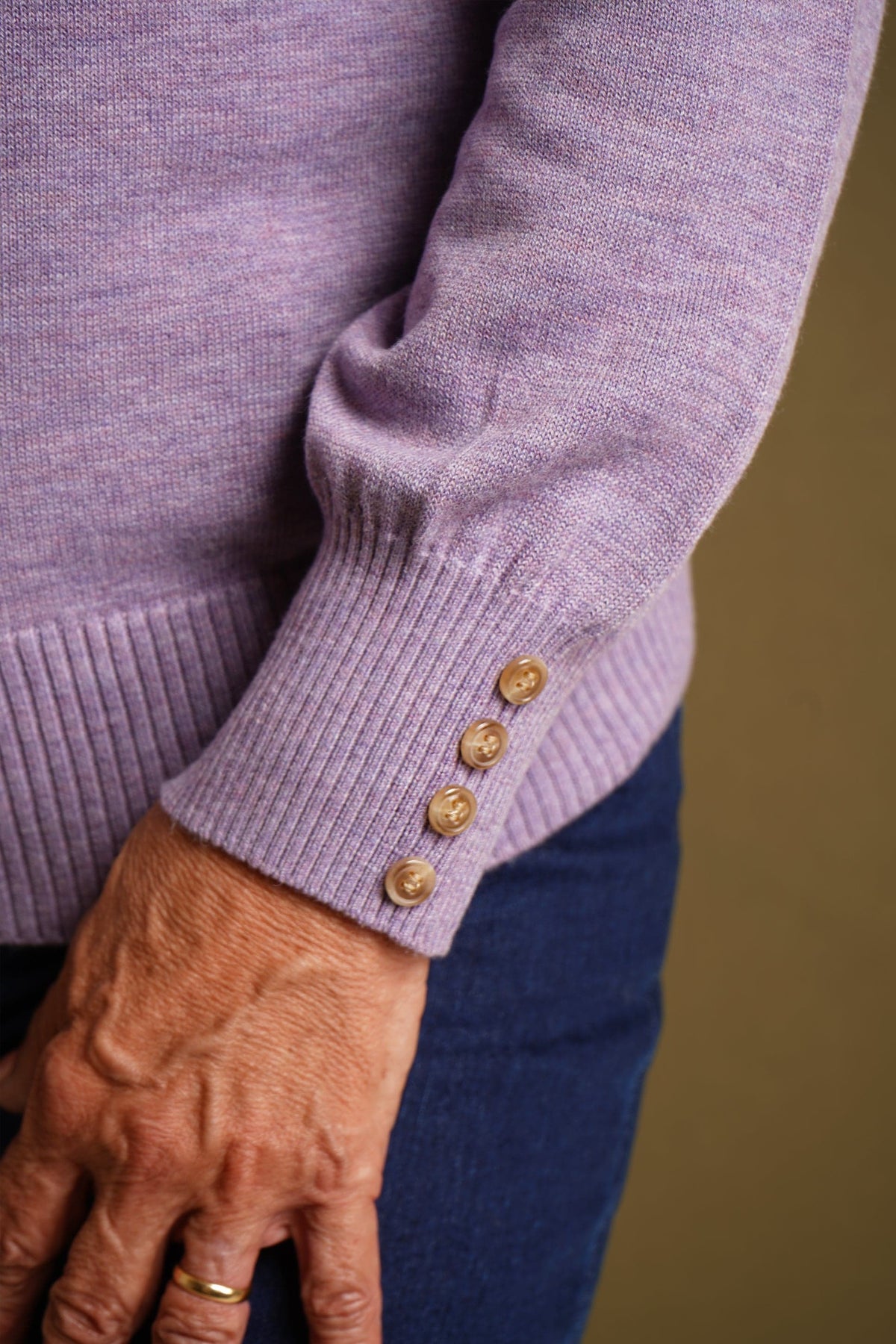 Woman wearing a long sleeve knitted jumper with a funnel collar, buttons along one side of the neck and buttoned ribbed cuffs._7