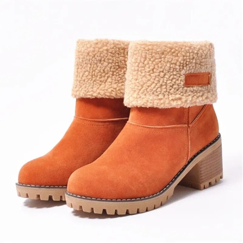 Orange ankle boots paired together on a white background, with contrasting cuff tabs, fold-over textured cuffs, rounded toes, and chunky block heels.