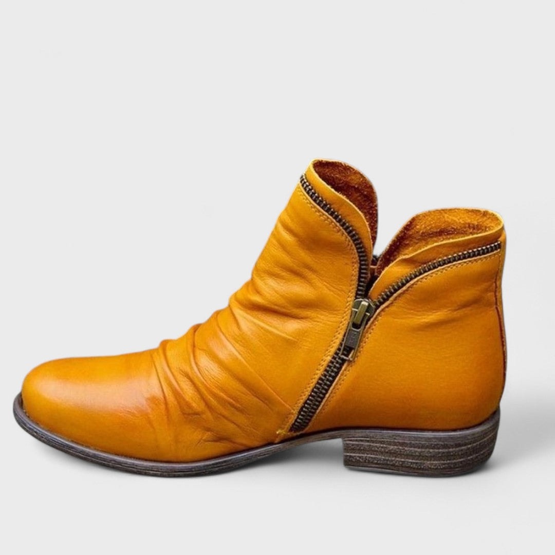 Golden yellow ankle boot in side profile with a curved side zipper, gathered upper texture, rounded toe, and grounded low heel.
