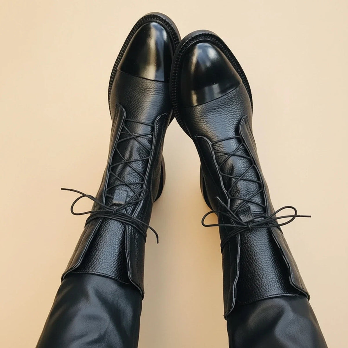 Pair of black ankle boots shown from above, featuring pointed toes and crisscross lacing across the fronts.