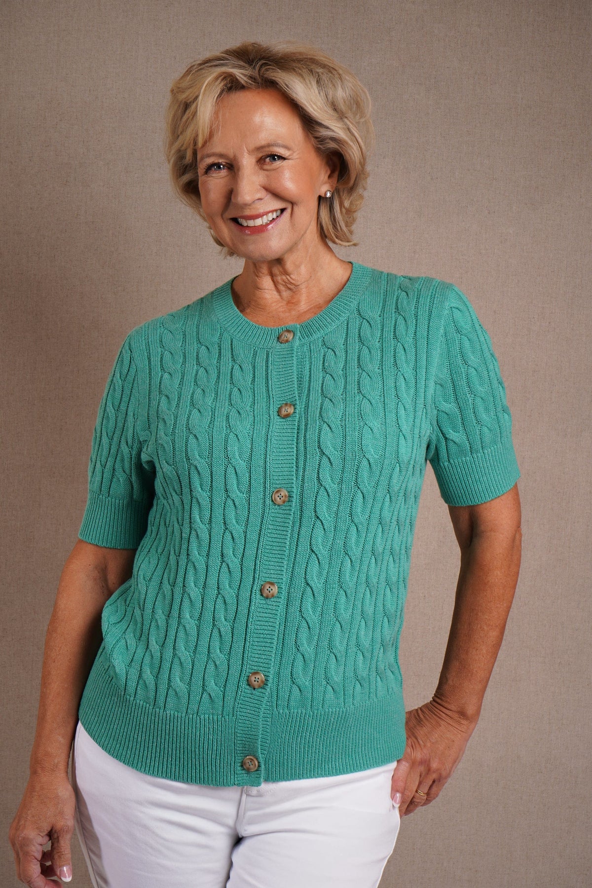 Short sleeve cable knit cardigan with round neckline, ribbed cuffs and hem, and a full row of front buttons._0