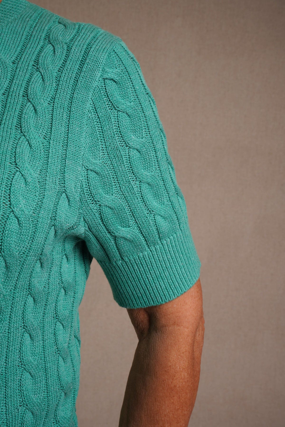 Short sleeve cable knit cardigan with round neckline, ribbed cuffs and hem, and a full row of front buttons._10