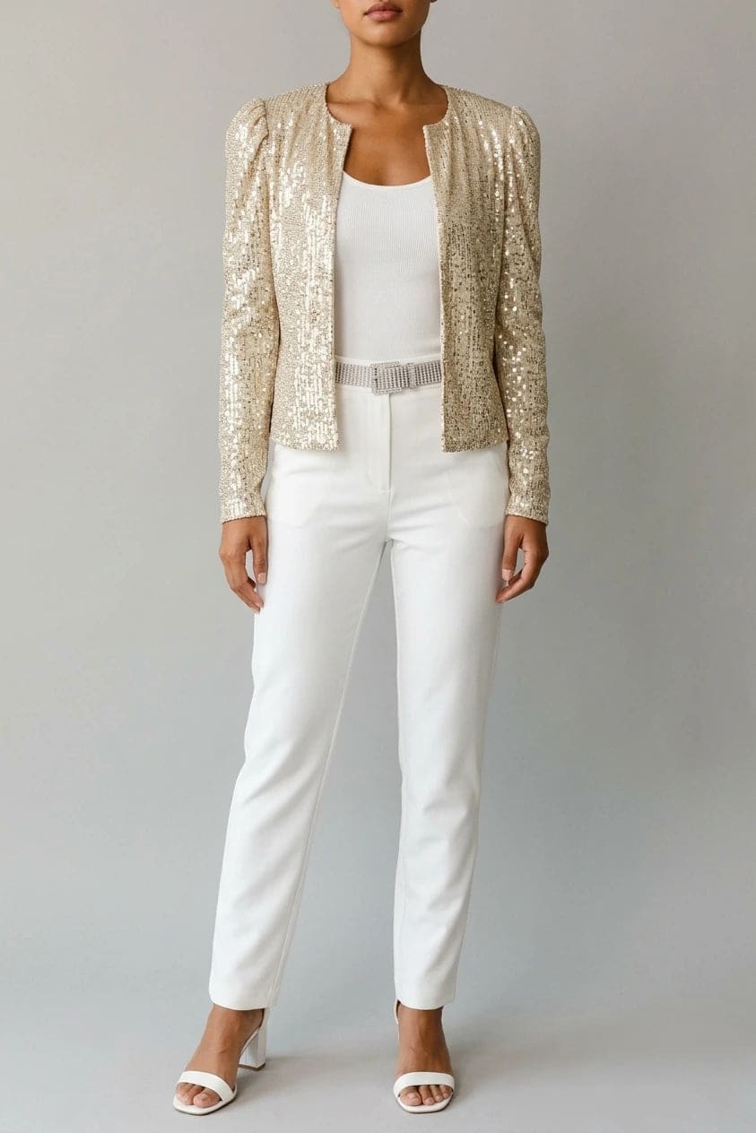 Model wearing an open-front cropped sequin jacket with long sleeves and structured shoulders over a tank top and tailored trousers._0
