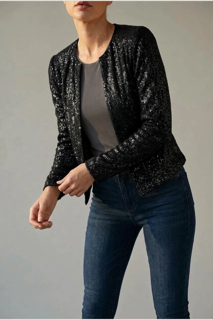 Model wearing an open-front cropped sequin jacket with long sleeves and structured shoulders over a tank top and tailored trousers._2