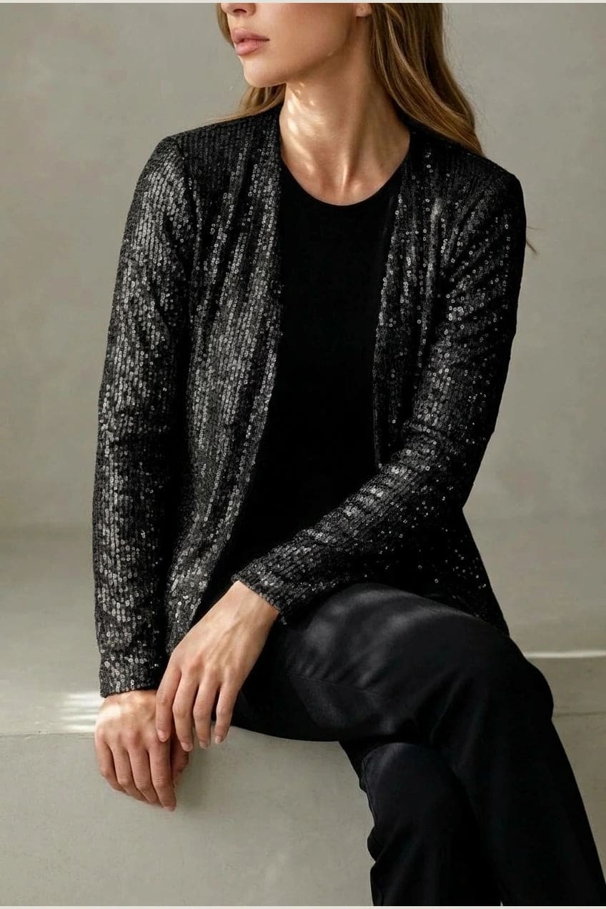 Model wearing an open-front cropped sequin jacket with long sleeves and structured shoulders over a tank top and tailored trousers._5