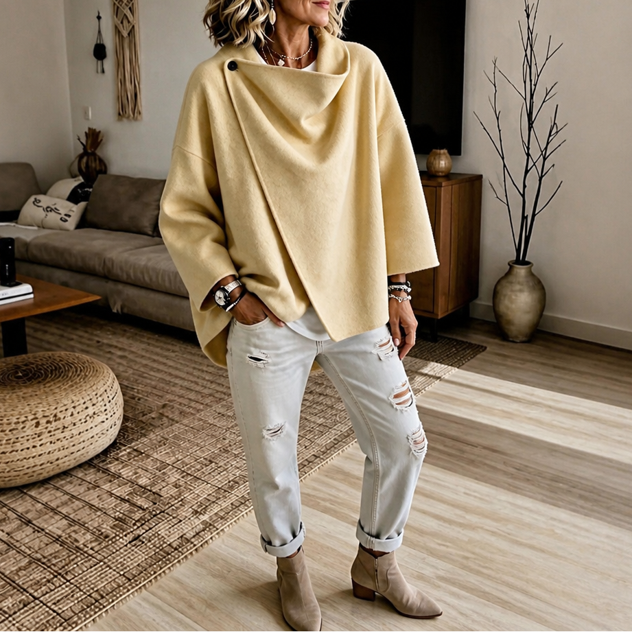 Mirror view of the asymmetric cape jacket in yellow, showing its sculptural collar and loose cape silhouette.