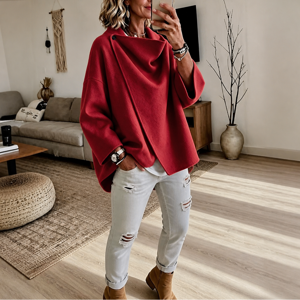 Mirror view of the asymmetric cape jacket in red, showing its dramatic draped front and wide sleeves.