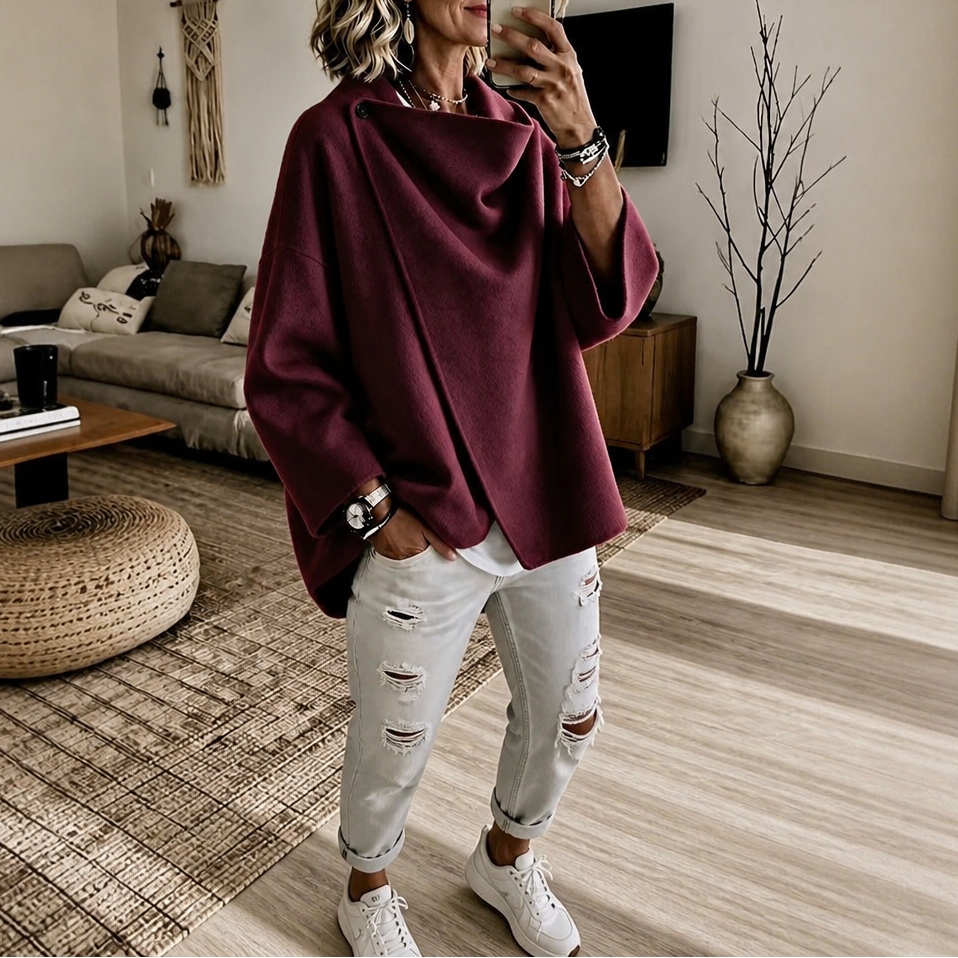 Mirror view of the asymmetric cape jacket in deep burgundy, styled with cuffed white jeans and sneakers.