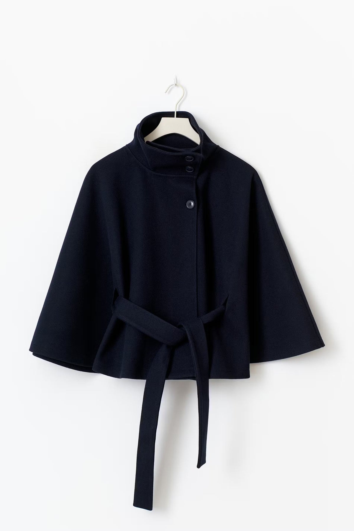 Navy cape jacket shown front-facing on a hanger with the raised collar, button closure, flared sleeves, and long tie belt.