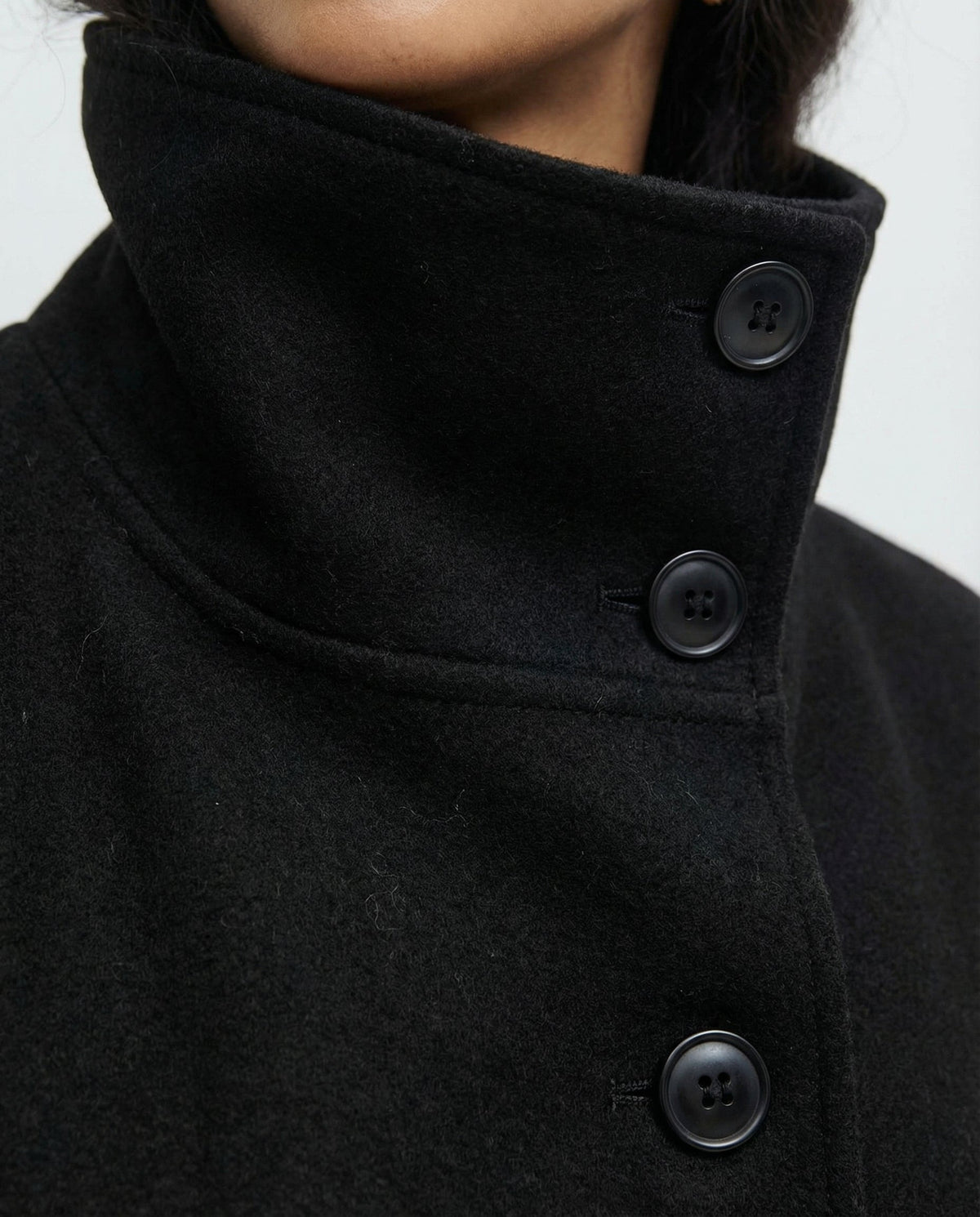 Close-up of the jacket’s high stand collar and dark buttons along the front fastening.