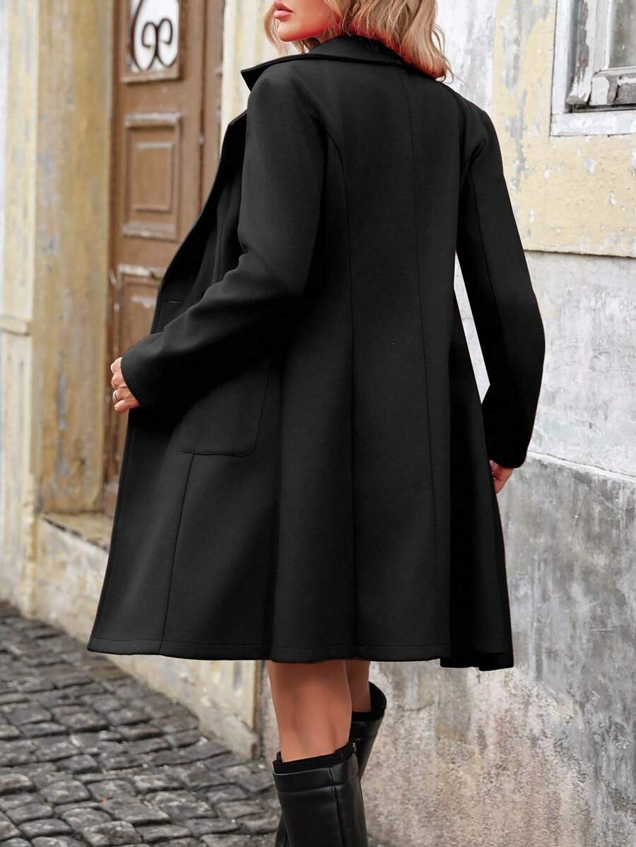 Woman wearing a long double breasted coat with notch lapels and patch pockets, standing on a cobbled street._2