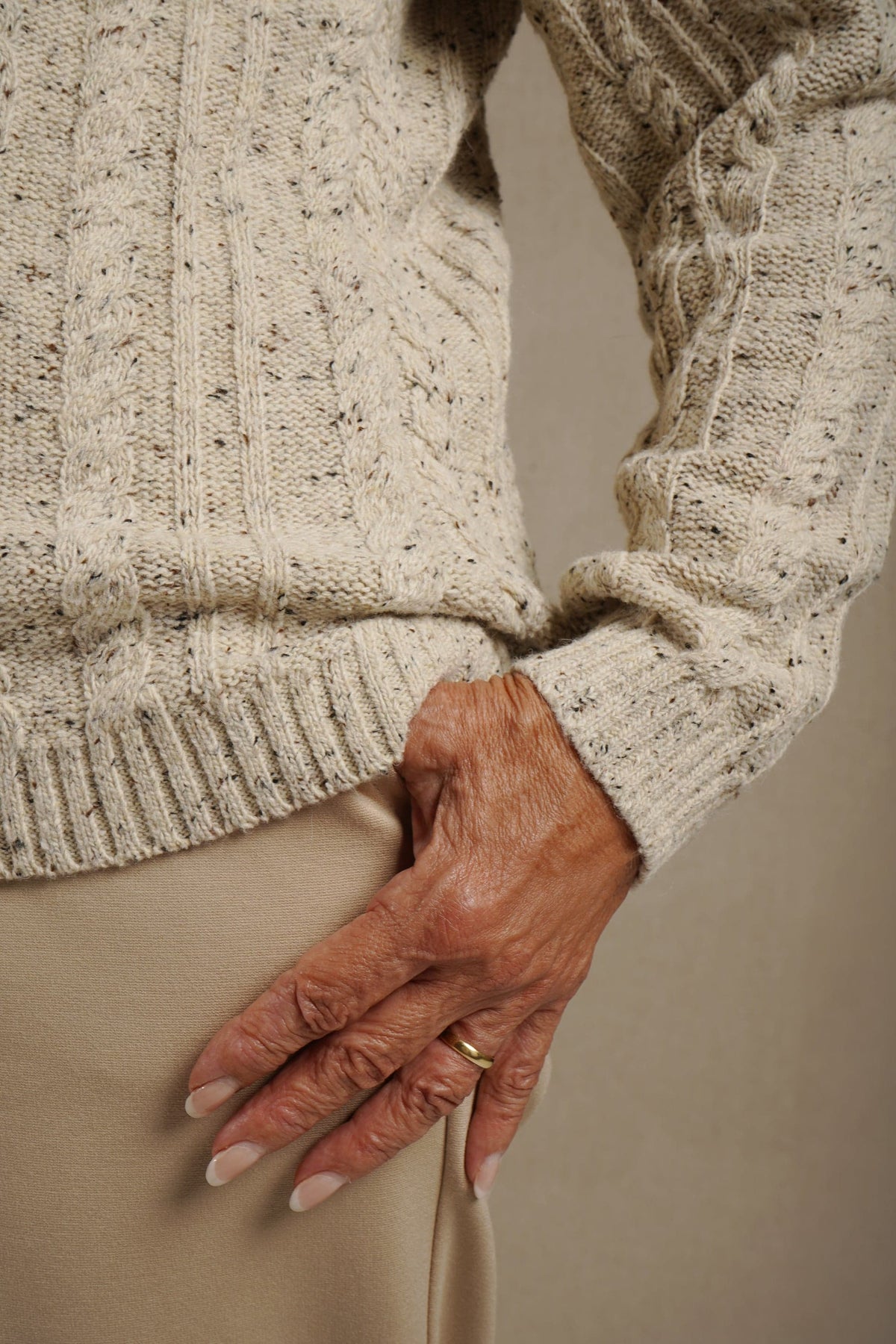 Woman wearing a long-sleeved cable knit cardigan with round neck, full button front and ribbed cuffs and hem._2