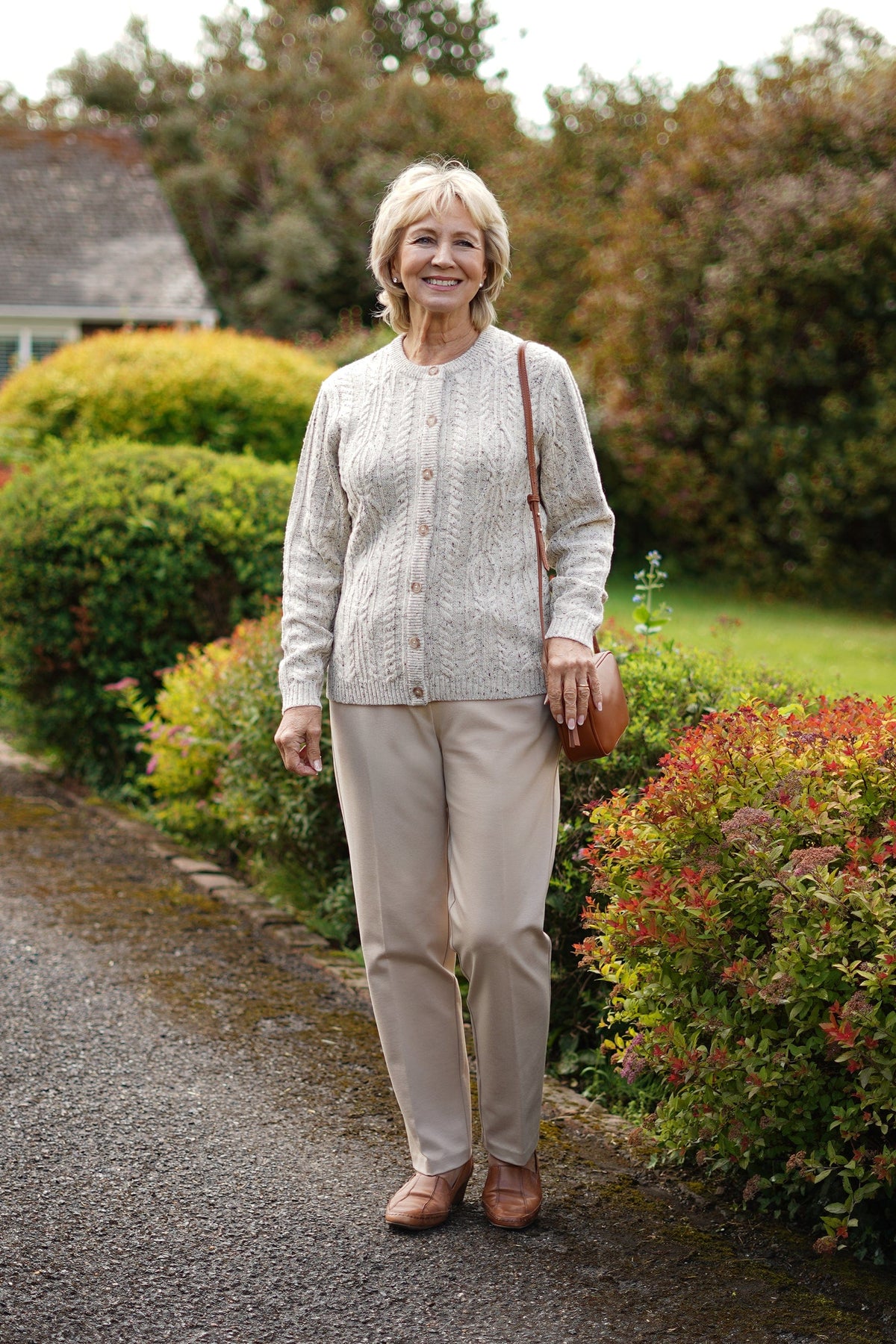 Woman wearing a long-sleeved cable knit cardigan with round neck, full button front and ribbed cuffs and hem._3