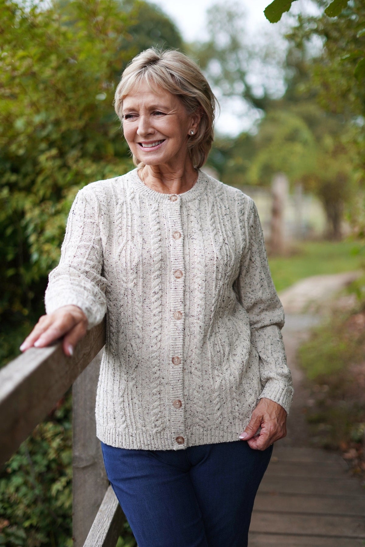 Woman wearing a long-sleeved cable knit cardigan with round neck, full button front and ribbed cuffs and hem._4