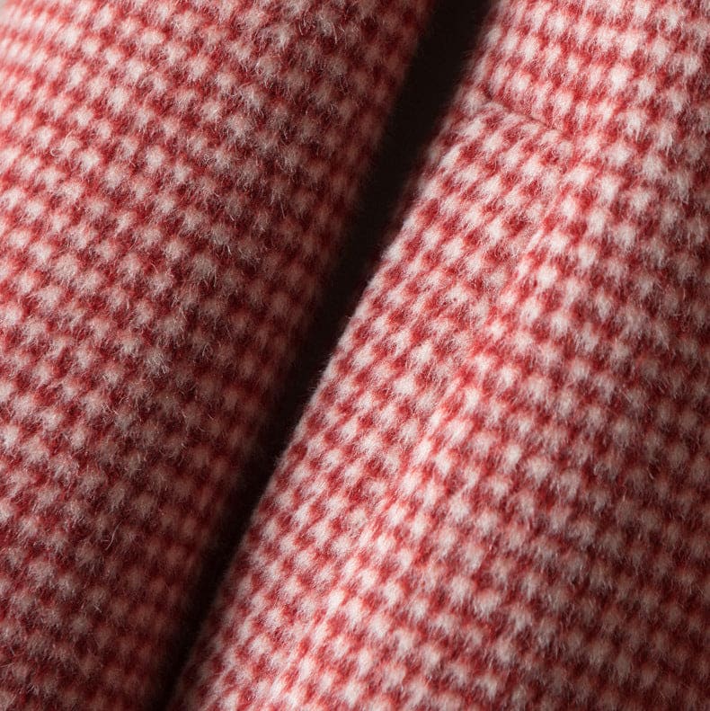 A longline check coat with a point collar, button front, and side pockets displayed on a hanger._4