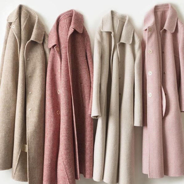A longline check coat with a point collar, button front, and side pockets displayed on a hanger._5