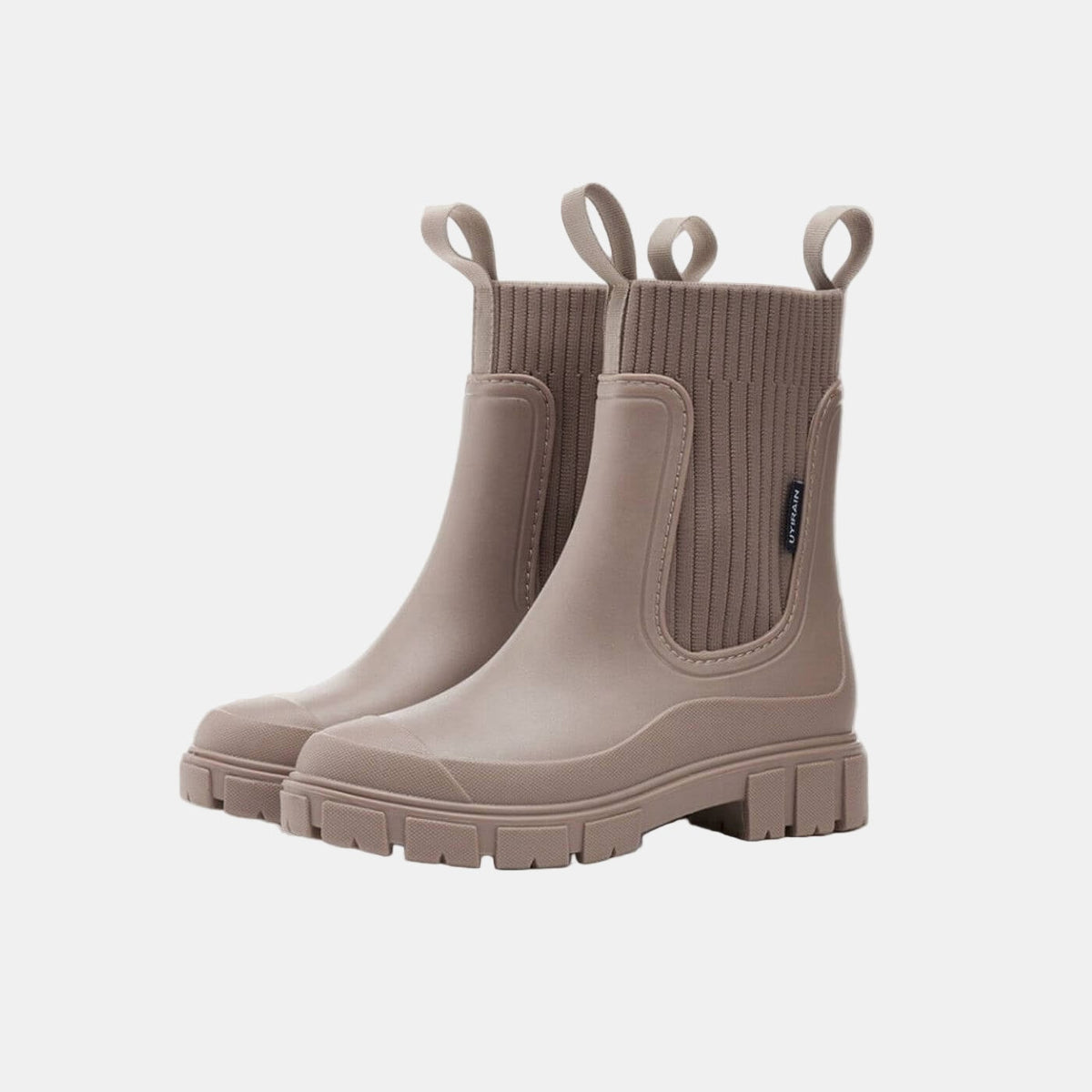 Pair of taupe Chelsea boots with ribbed elastic side panels, pull tabs, and chunky deeply treaded soles.