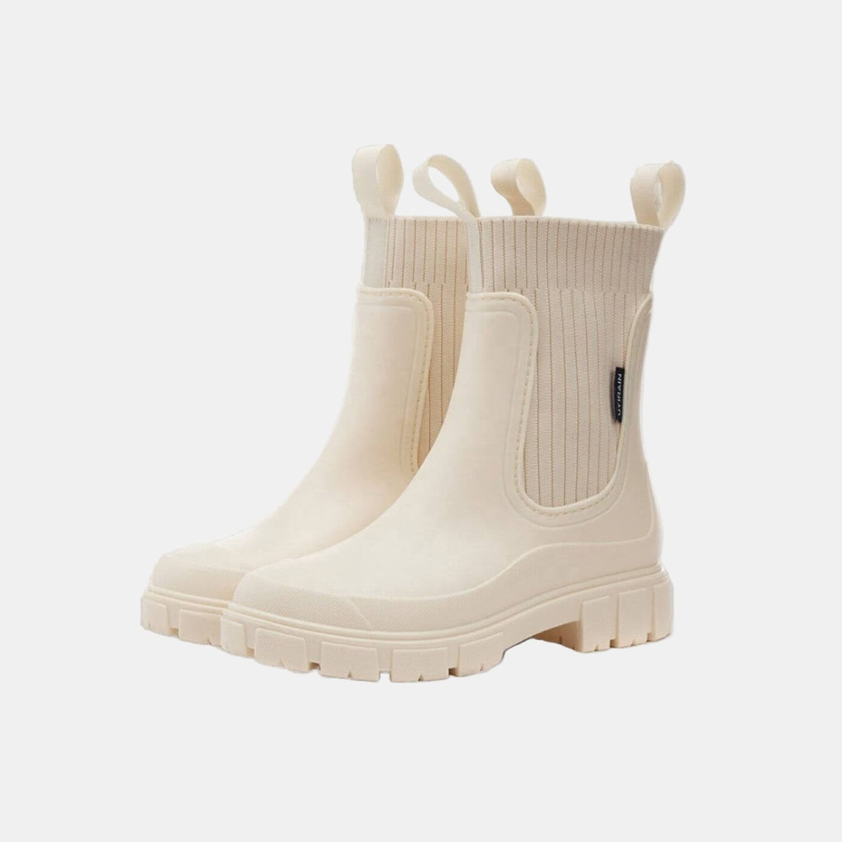 Pair of cream Chelsea boots with ribbed elastic side panels, pull tabs, and chunky treaded soles.