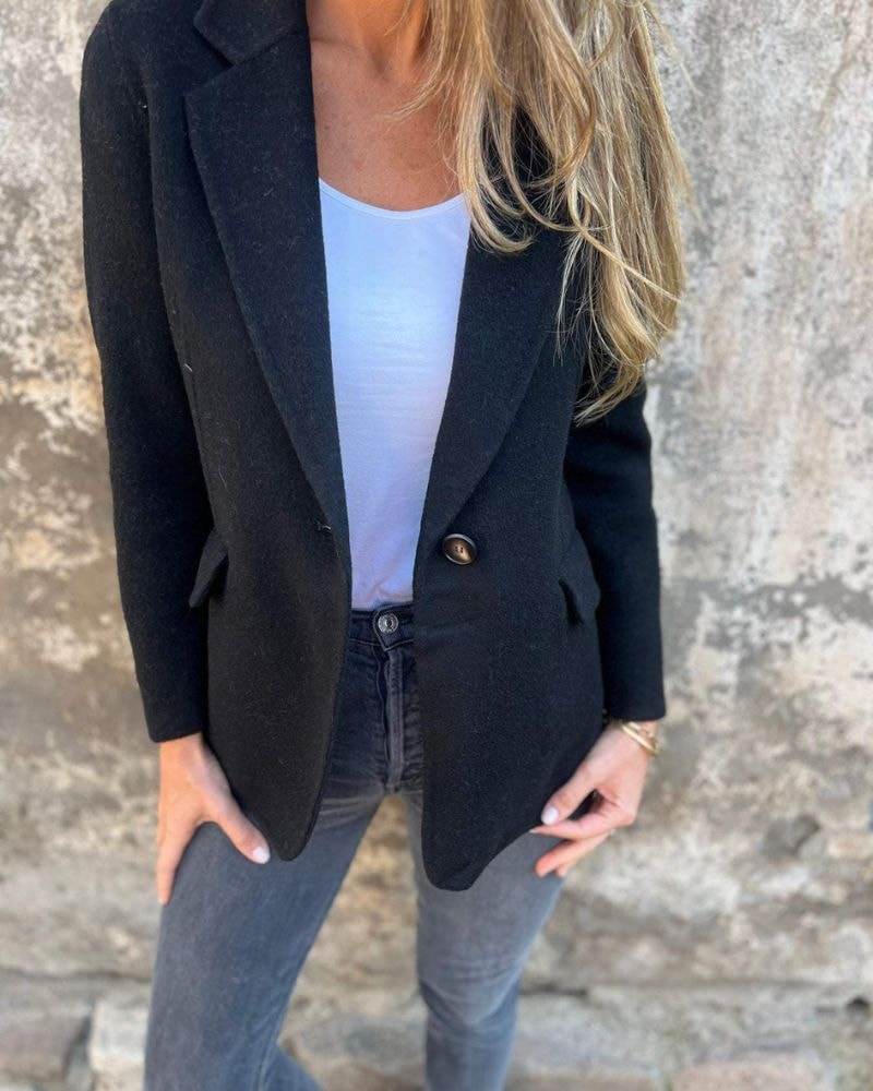 Black blazer jacket styled with a white top and dark jeans, showing the notched lapels and fastened single-button front.
