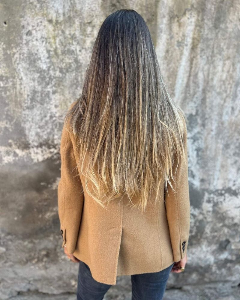 Back view of the tan blazer jacket, showing its straight back, long sleeves, and rounded lower hem.