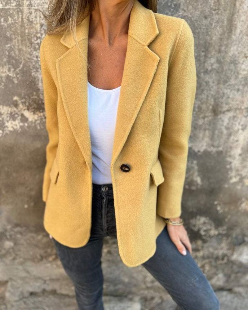 Golden yellow blazer jacket with notched lapels, a single dark button, and flap pockets worn with dark jeans.