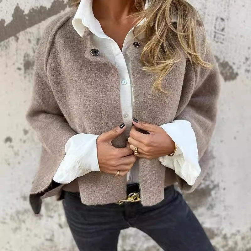 Taupe collarless button-front jacket worn over a white collared shirt, with the front being fastened by hand.