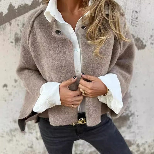Taupe collarless button-front jacket worn over a white collared shirt, with the front being fastened by hand.