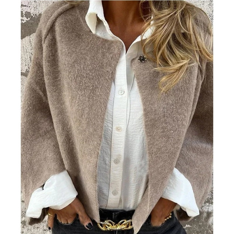 Close front view of the taupe collarless jacket worn open over a white button-down shirt.