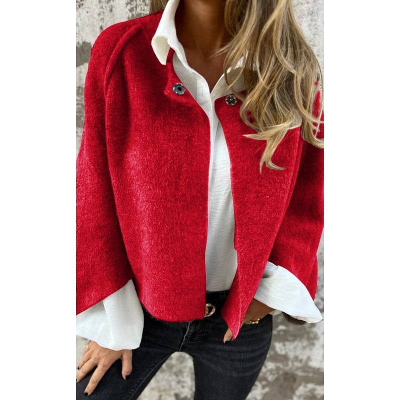 Bright red collarless button-front jacket worn open over a white shirt and dark jeans.