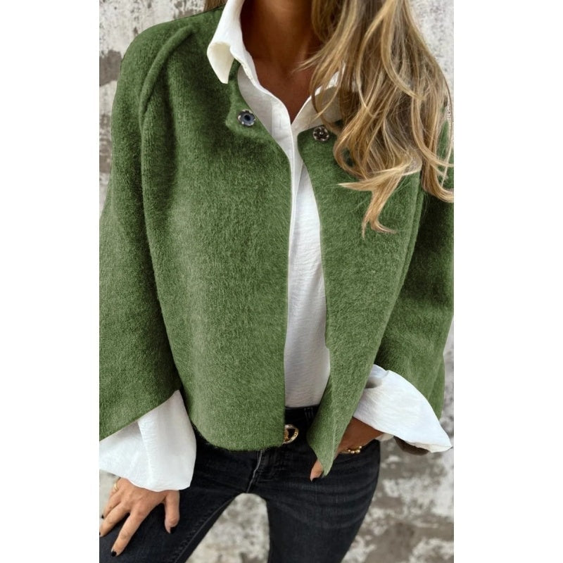 Green collarless jacket styled open over a white collared shirt.