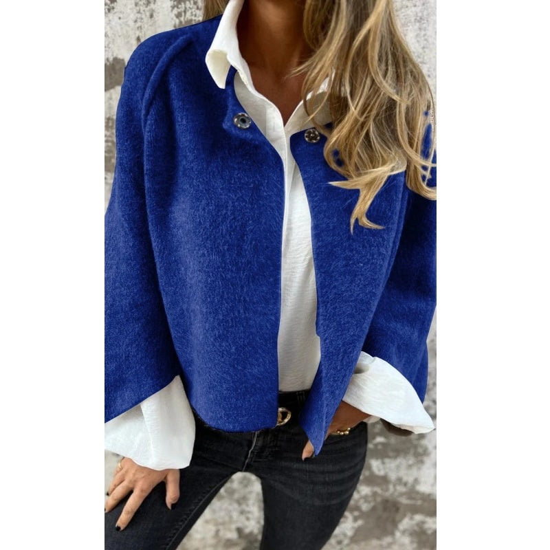 Royal blue collarless button-front jacket worn open with a white shirt and dark jeans.