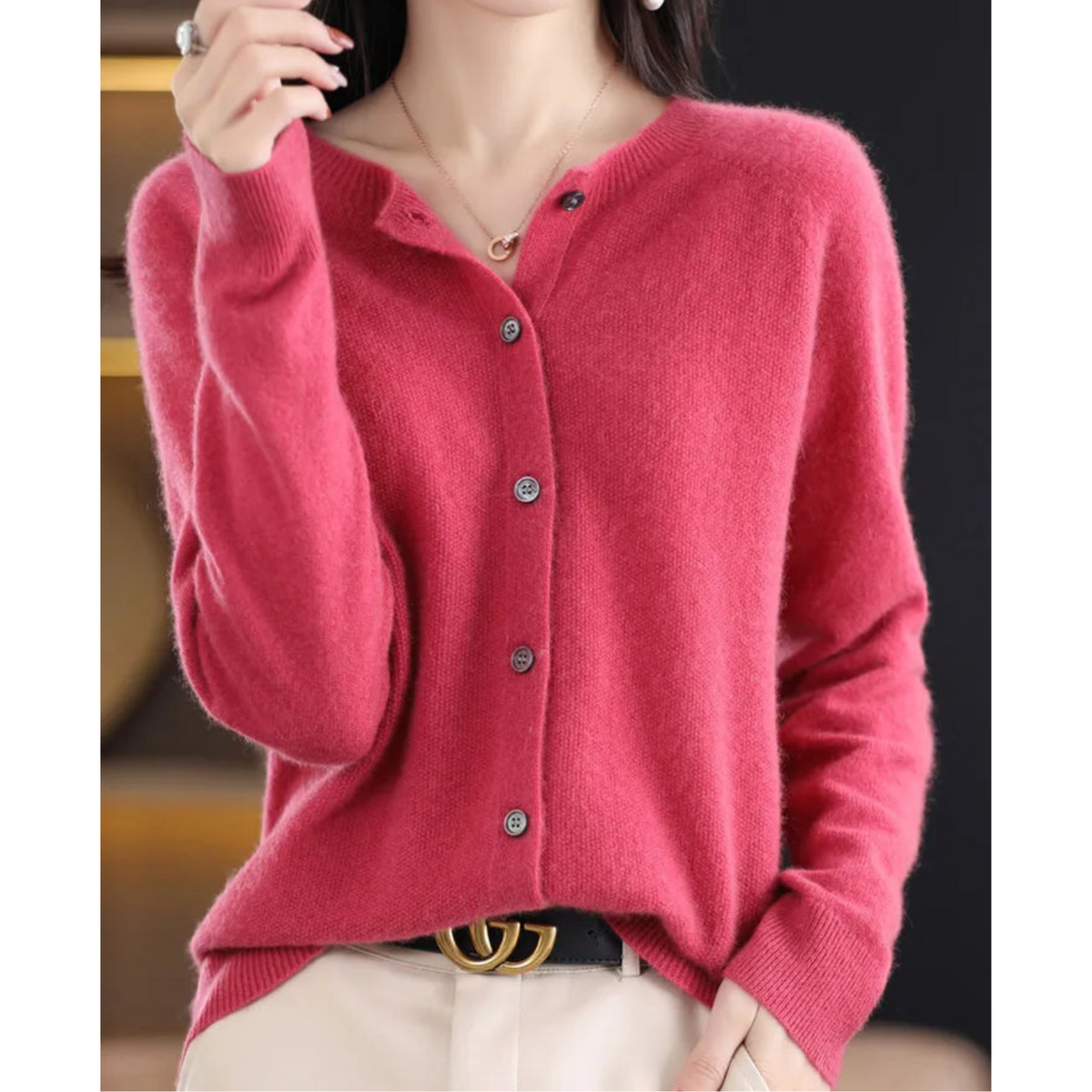 Pink crew neck button-front cardigan styled with cream trousers and a black belt