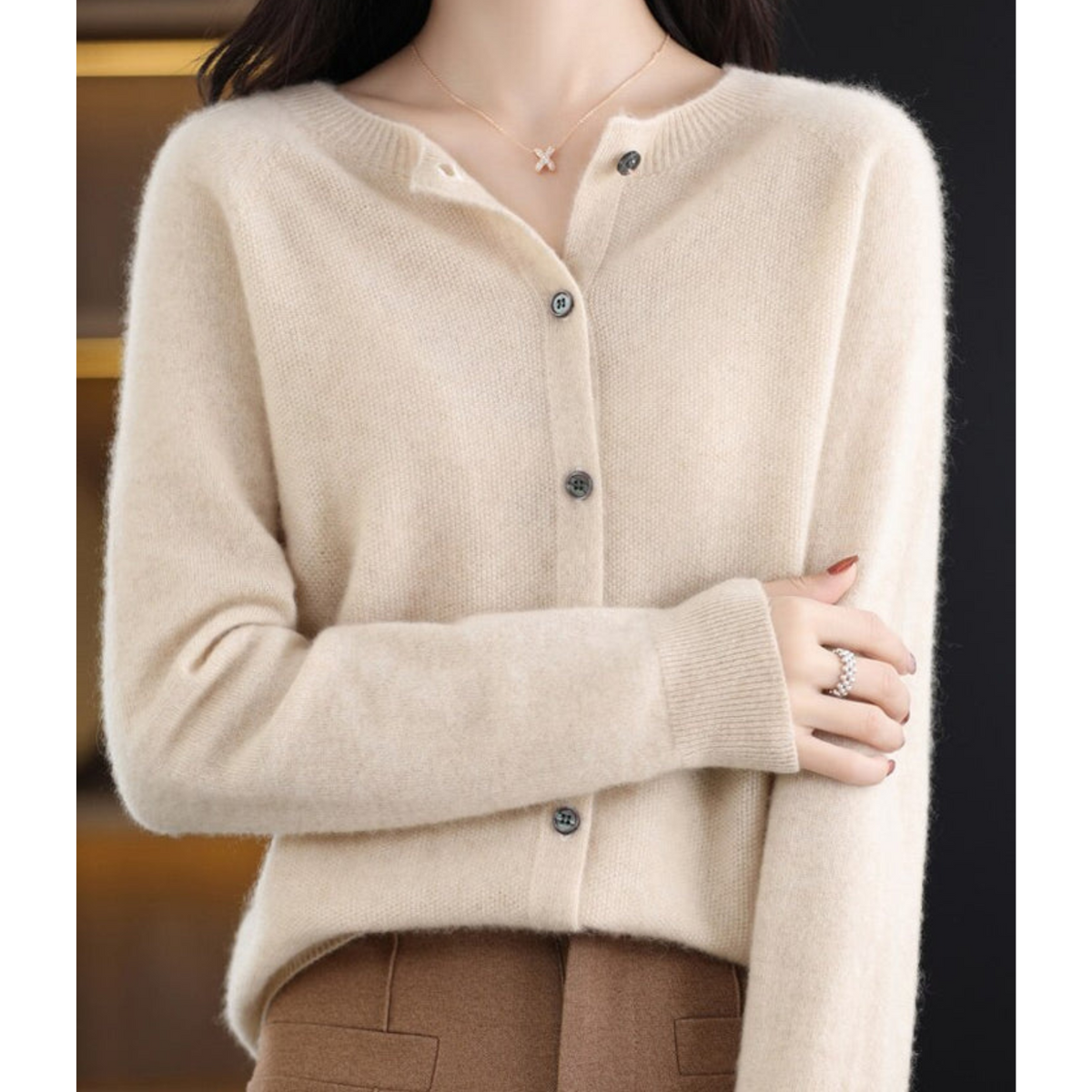 Cream cardigan with crossed arms, ribbed cuffs, and a button-front closure