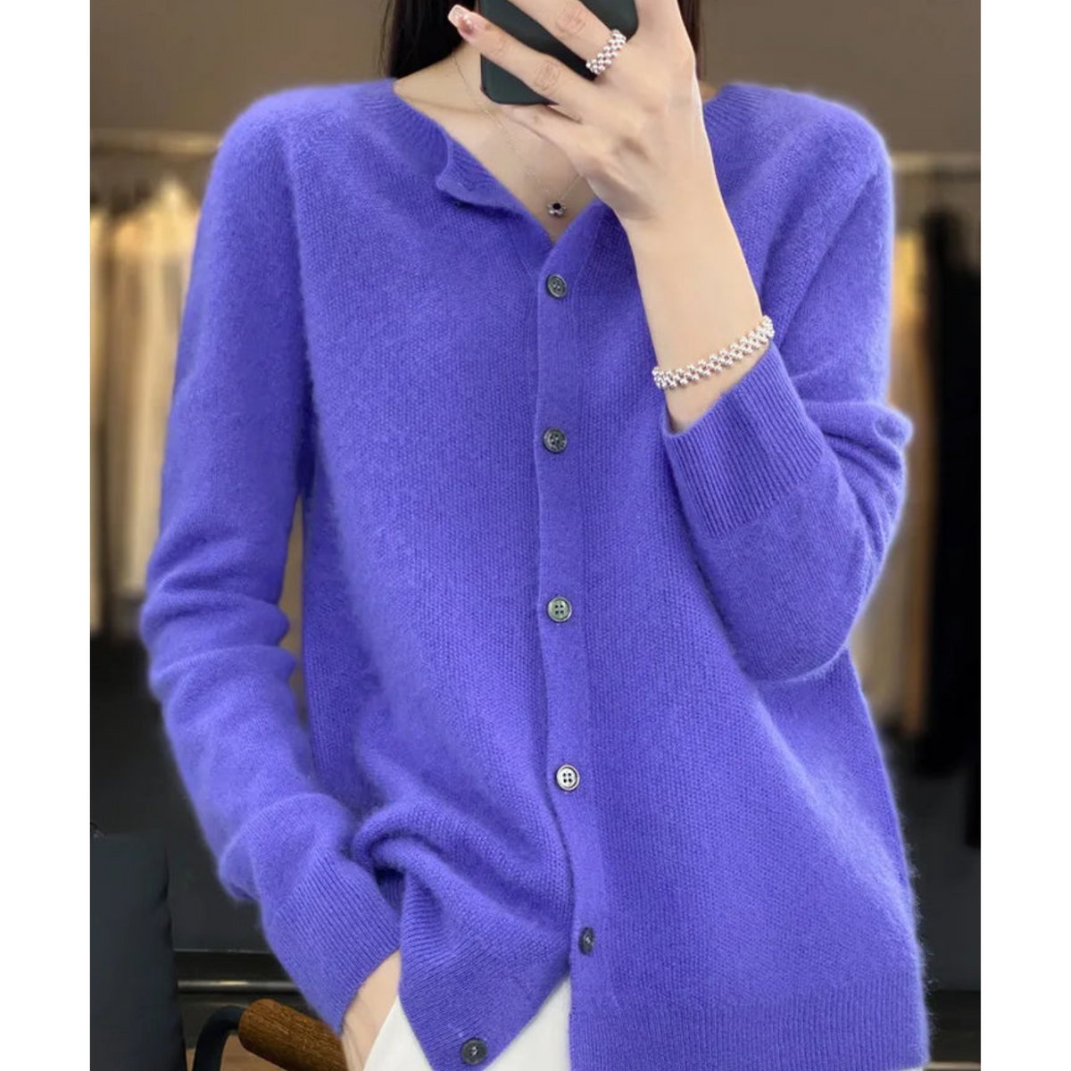Violet button-front cardigan shown with one hand in a pocket and the other holding a phone