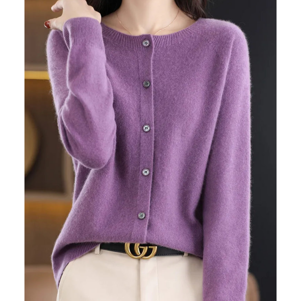 Purple crew neck cardigan worn with cream trousers and a black belt