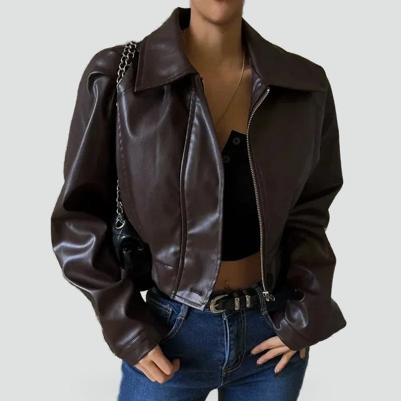 Dark brown cropped biker jacket worn open over a black top, showing its wide collar, relaxed shoulders, and asymmetric front zip.