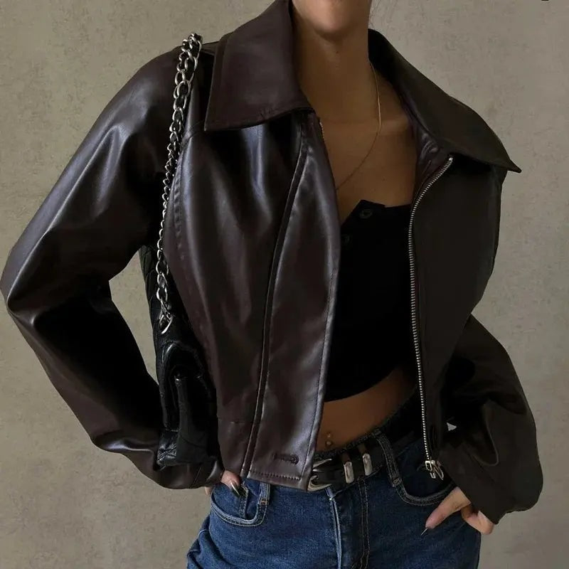 Close-up of the cropped dark brown biker jacket styled with jeans, highlighting the broad open collar, angled zip, and relaxed sleeves.