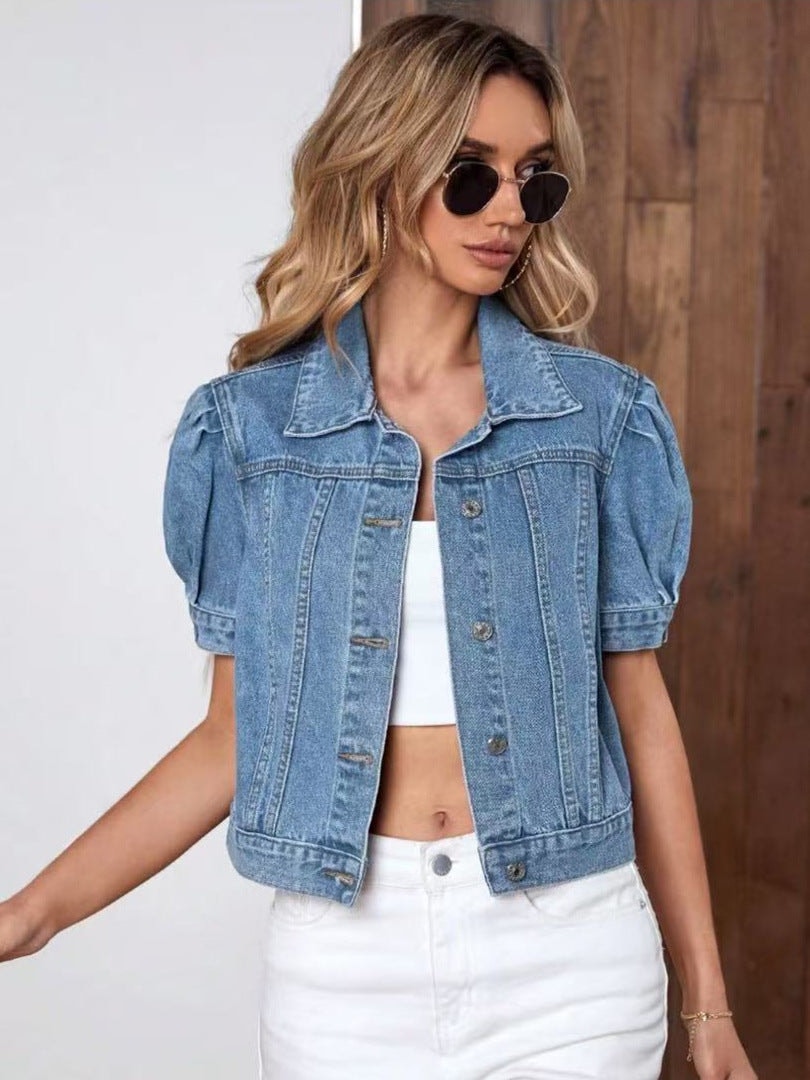 Light blue cropped jacket shown in a slightly angled front view with rolled sleeve cuffs, chest pockets, and a button closure.