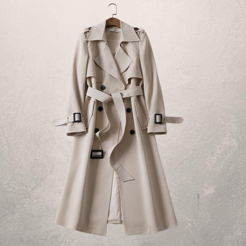 Light beige double-breasted trench coat on a hanger with a tied waist belt, wide lapels, and buckled cuff straps.